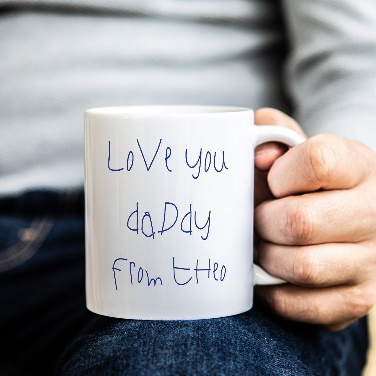 Person holding a white mug with 'Love you Daddy' in childs own handwriting