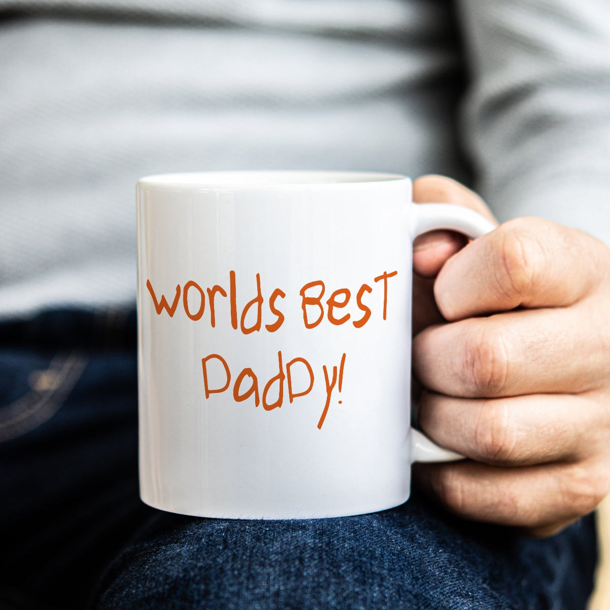Person holding a white mug with 'Worlds Best Dad' text, in childs own handwriting